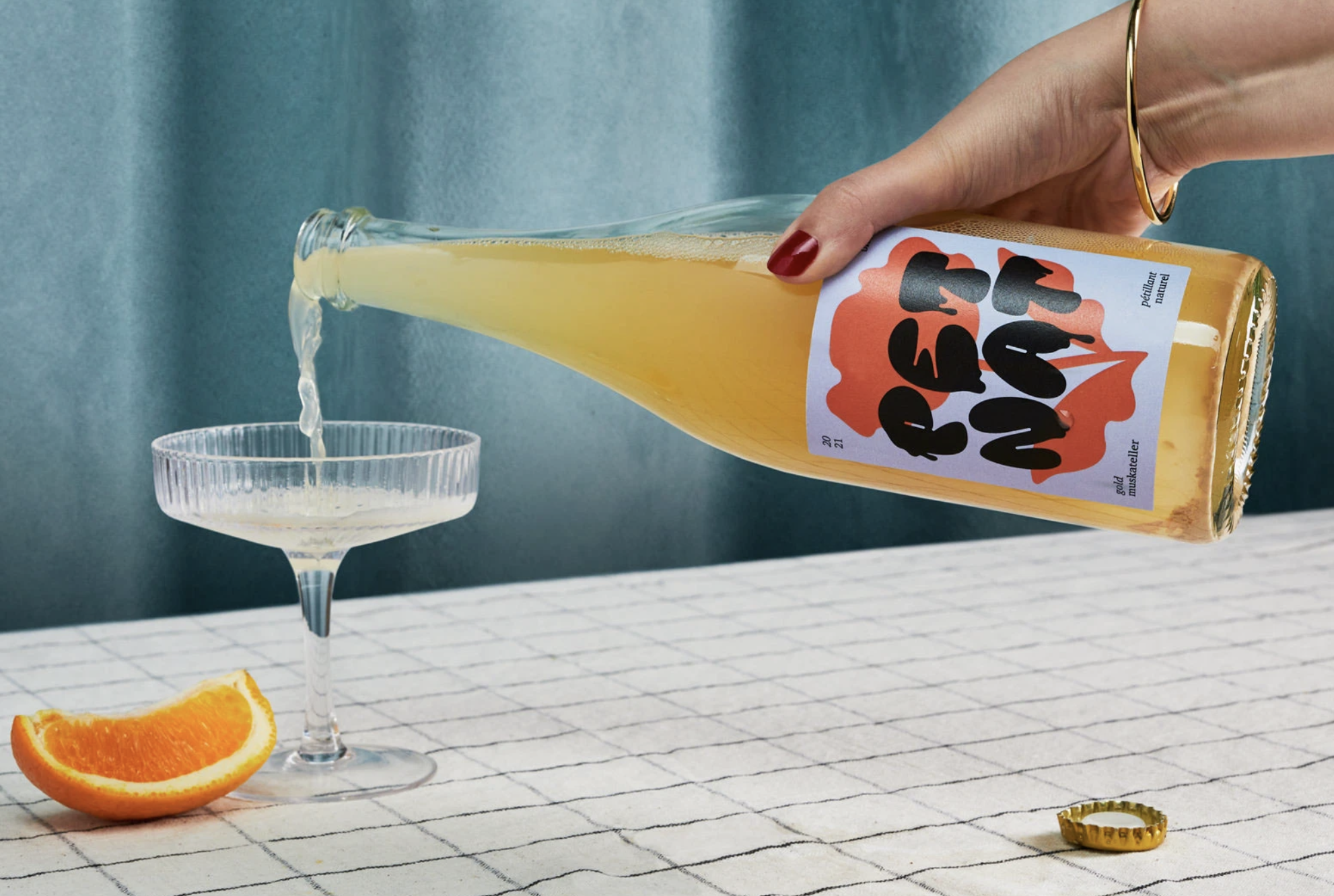 golden Pet Nat sparkling wine from a bottle into a coupe glas